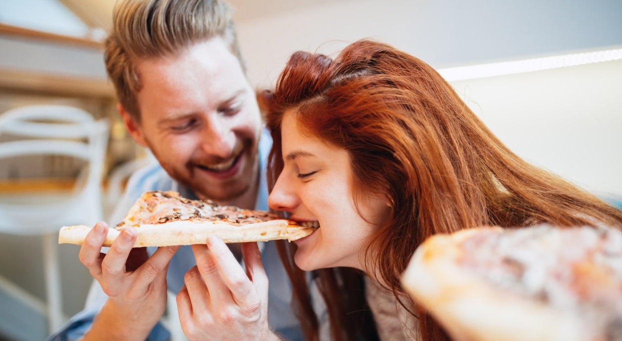 Couple sharing pizza and eating