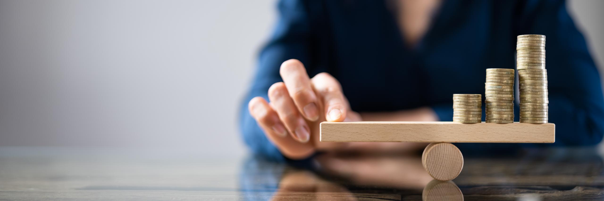 Businessperson Balancing Stacked Coins On Seesaw