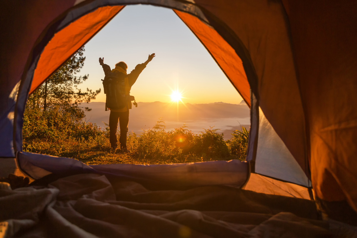 randonneur-debout-devant-tente-orange-devant-camping-sac-dos-montagne