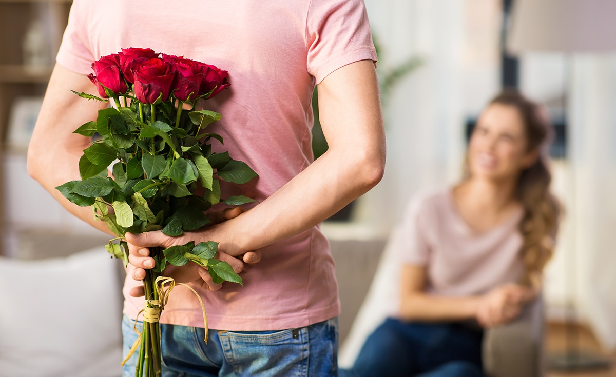 woman and man with bunch of roses behind his back